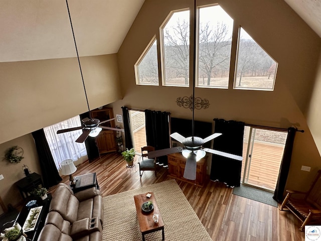 living area with ceiling fan, high vaulted ceiling, and wood finished floors