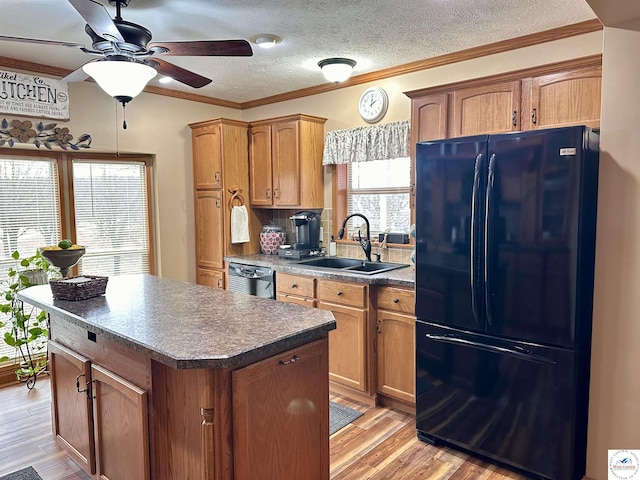 kitchen featuring a center island, crown molding, light wood finished floors, a sink, and black appliances