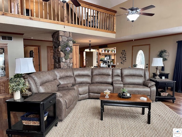 living room with visible vents, a ceiling fan, ornamental molding, wood finished floors, and a high ceiling