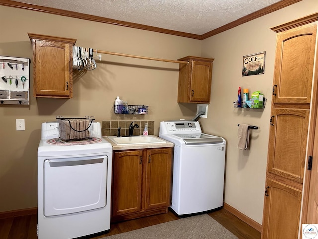 clothes washing area with a textured ceiling, a sink, ornamental molding, cabinet space, and washer and clothes dryer