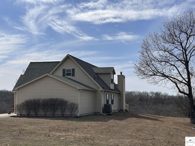 view of side of property featuring roof with shingles and a chimney