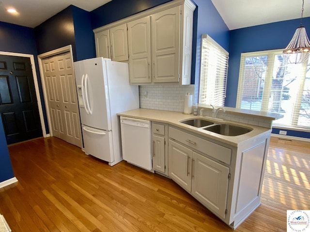 kitchen featuring white appliances, light countertops, white cabinetry, pendant lighting, and a sink