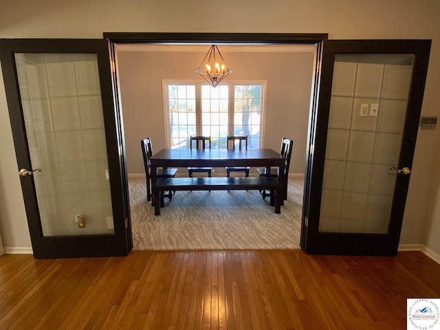 dining area with a chandelier, wood finished floors, and baseboards