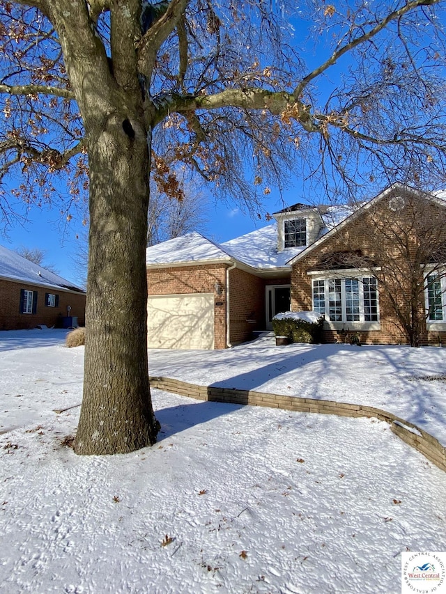 view of front of house with a garage, brick siding, and driveway