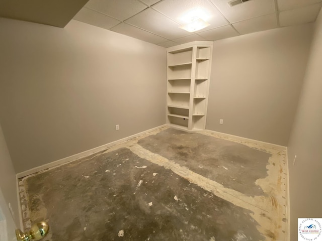 empty room featuring visible vents, baseboards, concrete flooring, and a drop ceiling