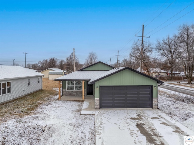 view of front of house featuring a garage, stone siding, roof with shingles, and driveway