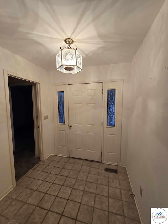 tiled entrance foyer with visible vents and baseboards