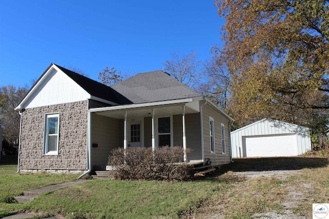 view of front of home featuring stone siding, a front lawn, covered porch, and an outbuilding