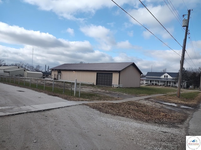 exterior space with metal roof, fence, a garage, driveway, and an outdoor structure