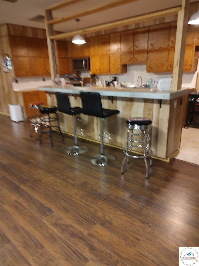 kitchen featuring light countertops, a breakfast bar area, a peninsula, and brown cabinetry