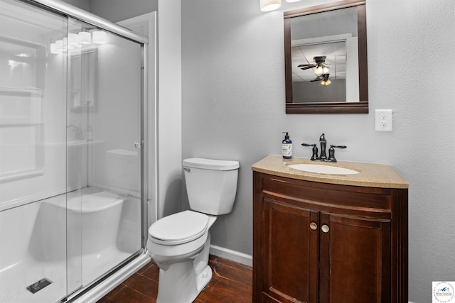 full bath featuring vanity, wood finished floors, a ceiling fan, a shower stall, and toilet