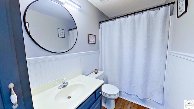 full bath featuring wainscoting, vanity, toilet, and wood finished floors