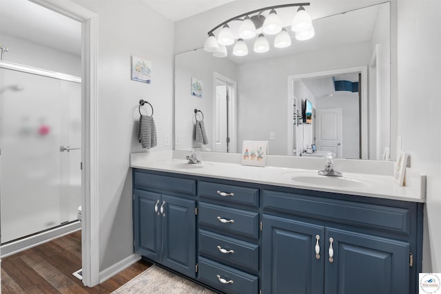 bathroom with double vanity, wood finished floors, a stall shower, and a sink