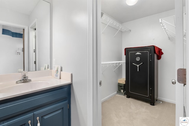 bathroom with baseboards, a spacious closet, and vanity