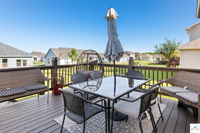 wooden terrace featuring a residential view, outdoor dining space, and a yard