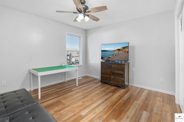 interior space with a ceiling fan, baseboards, and light wood finished floors