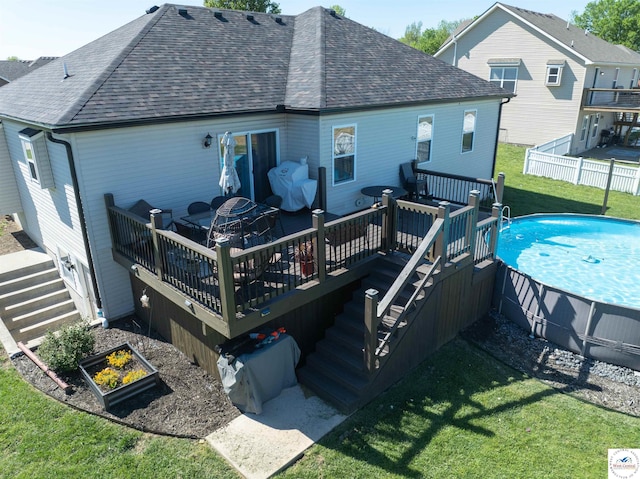 rear view of property with a lawn, fence, roof with shingles, and a fenced in pool