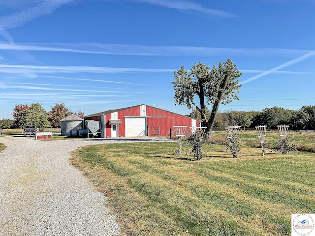 view of pole building with gravel driveway and a yard