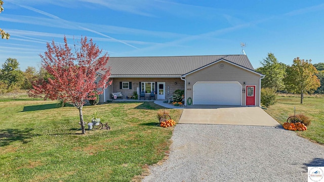 ranch-style house with metal roof, driveway, an attached garage, and a front yard