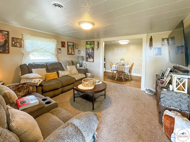 carpeted living area featuring visible vents and baseboards