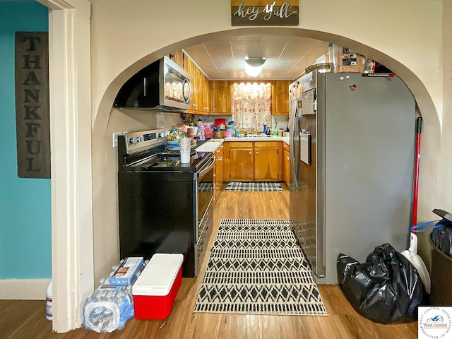 kitchen featuring a sink, light countertops, appliances with stainless steel finishes, light wood-type flooring, and brown cabinets