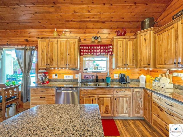 kitchen with dark stone counters, lofted ceiling, dark wood-type flooring, stainless steel dishwasher, and a sink