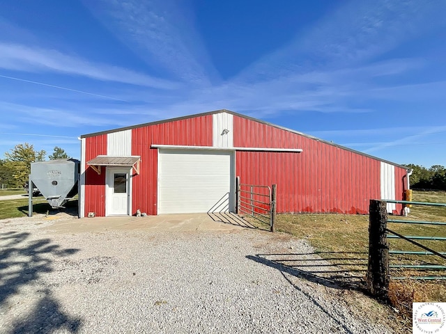 view of outdoor structure with gravel driveway, fence, and an outdoor structure