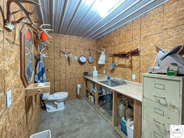 bathroom featuring toilet, concrete floors, and a sink