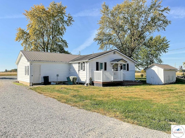 view of front facade with a storage shed, metal roof, a front lawn, and an outdoor structure