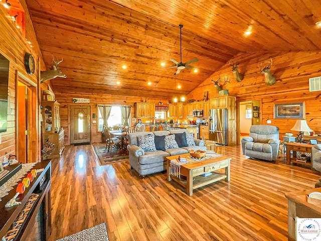 living area featuring light wood-style floors, ceiling fan, wooden walls, high vaulted ceiling, and wooden ceiling