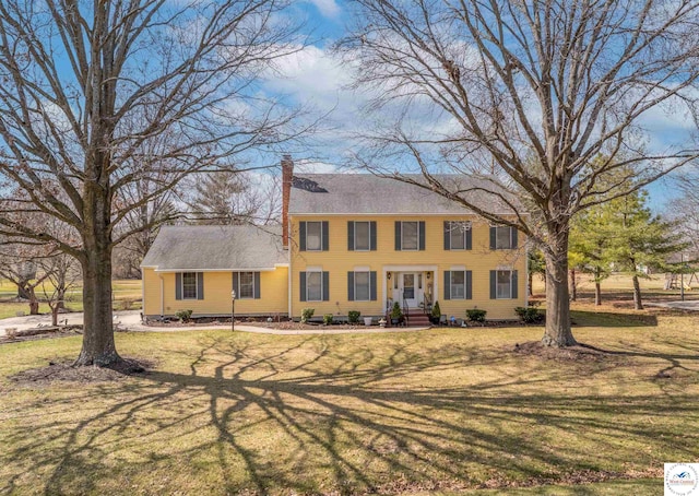 colonial inspired home featuring entry steps, a front lawn, and a chimney