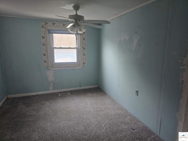 carpeted spare room featuring ornamental molding, visible vents, and ceiling fan