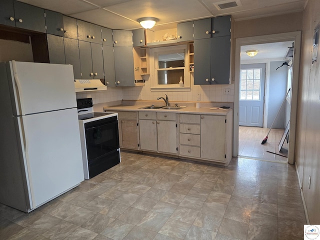 kitchen with under cabinet range hood, a sink, black electric range, light countertops, and freestanding refrigerator