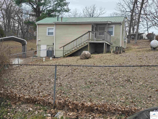 rear view of property with stairs, fence, metal roof, and a detached carport