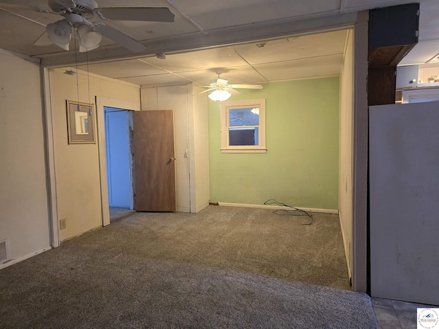 empty room with carpet floors, visible vents, and a ceiling fan