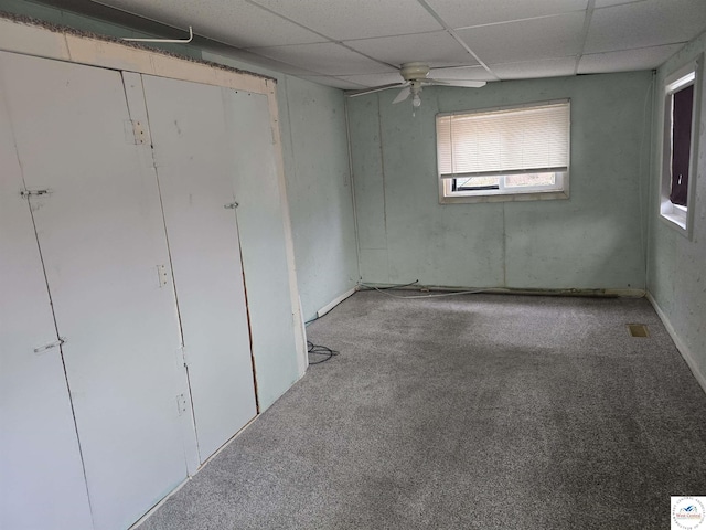 interior space featuring carpet floors, ceiling fan, and a drop ceiling