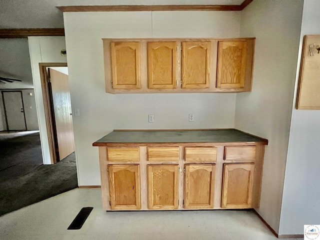 kitchen with light carpet, light brown cabinetry, and dark countertops