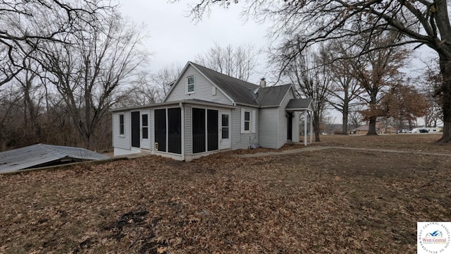 back of property featuring a chimney and a sunroom