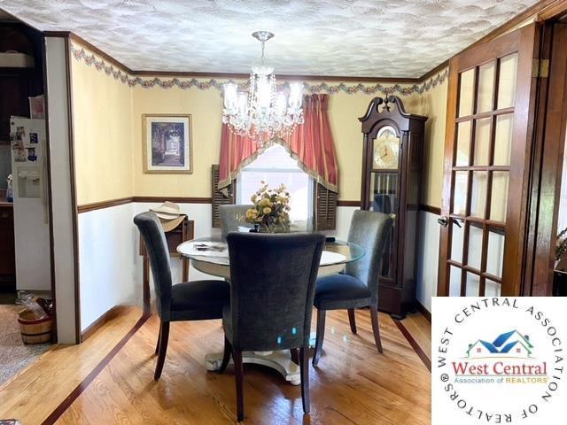 dining space featuring a textured ceiling, wood finished floors, and a notable chandelier