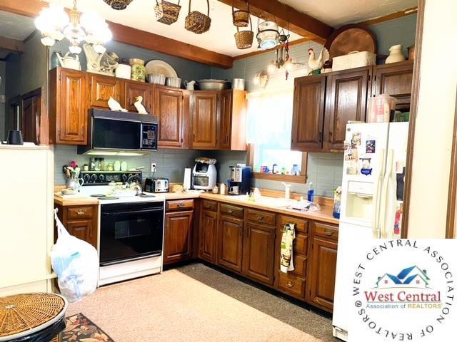 kitchen featuring black microwave, electric range, light countertops, beam ceiling, and tasteful backsplash