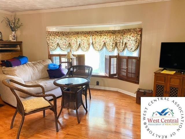 sitting room featuring baseboards, wood finished floors, and crown molding