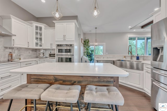 kitchen featuring glass insert cabinets, appliances with stainless steel finishes, white cabinetry, and a breakfast bar