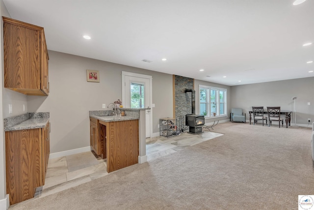 bar with light carpet, a wood stove, a healthy amount of sunlight, and a sink