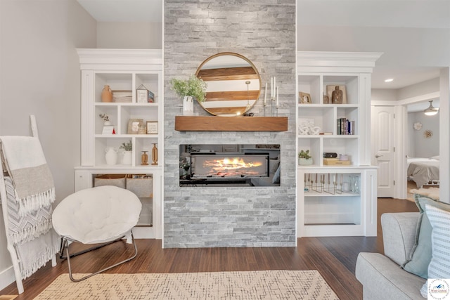 living area featuring a large fireplace, wood finished floors, and built in features