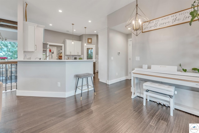 kitchen with dark wood-style floors, hanging light fixtures, light countertops, white cabinetry, and a notable chandelier