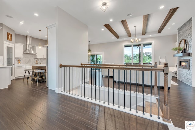 interior space with dark wood finished floors, a notable chandelier, a fireplace, beam ceiling, and recessed lighting