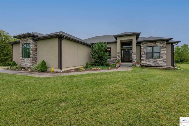 prairie-style home with a front yard, stone siding, and stucco siding