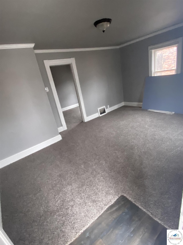 unfurnished room with dark colored carpet, visible vents, crown molding, and baseboards