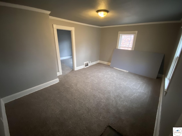 empty room with ornamental molding, carpet, visible vents, and baseboards