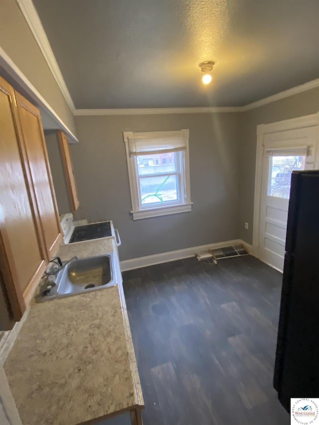 kitchen featuring crown molding, dark wood finished floors, light countertops, freestanding refrigerator, and a sink